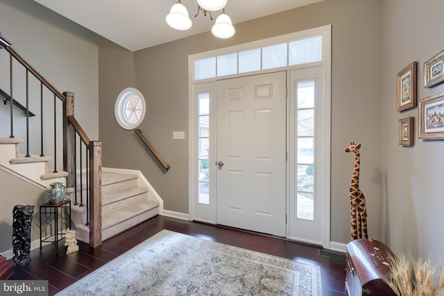 foyer entrance featuring a healthy amount of sunlight, baseboards, stairway, and dark wood-style flooring