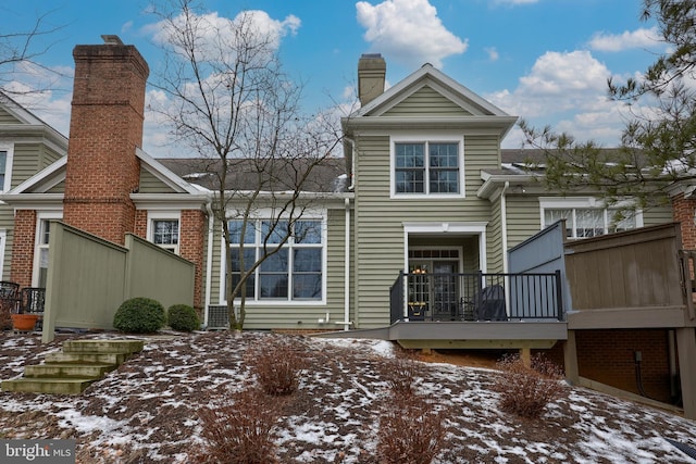 snow covered rear of property with a chimney