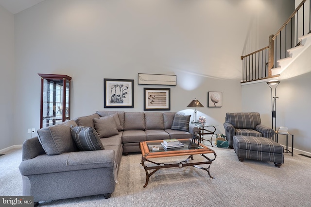 living area with light colored carpet, a towering ceiling, baseboards, and a wall mounted AC