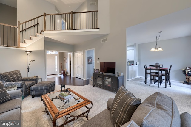 carpeted living room featuring baseboards, visible vents, and an inviting chandelier