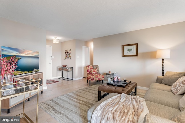 living room with light wood-type flooring, a textured ceiling, and baseboards