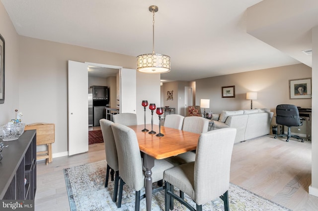 dining room featuring light wood finished floors, visible vents, and baseboards