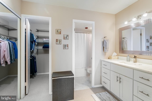 bathroom featuring baseboards, toilet, shower / tub combo with curtain, a spacious closet, and vanity