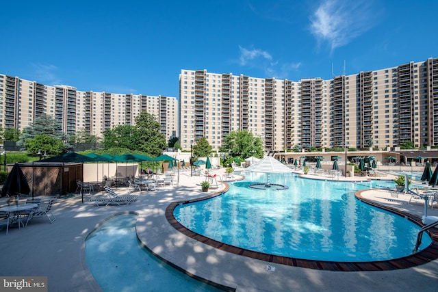 community pool with a patio area, a city view, and fence