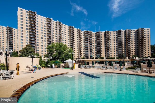 community pool with fence, a city view, and a patio