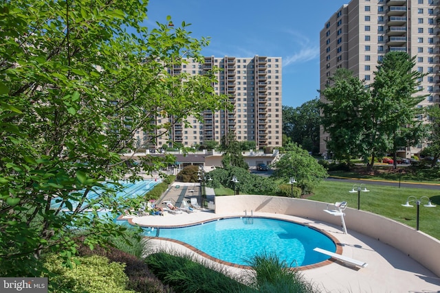 community pool with a diving board and a patio