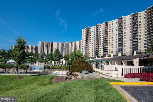 view of building exterior featuring a view of city, fence, and a community pool