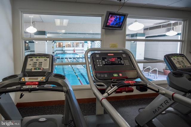 exercise room with a paneled ceiling and a healthy amount of sunlight