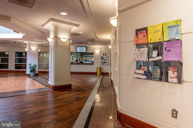 corridor with baseboards, dark wood-type flooring, and ornate columns