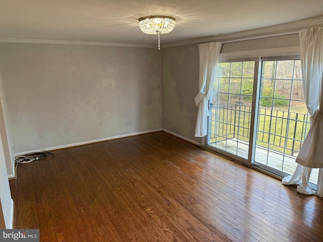 unfurnished room with a chandelier, baseboards, ornamental molding, and dark wood finished floors