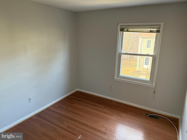 unfurnished room featuring visible vents, baseboards, and wood finished floors