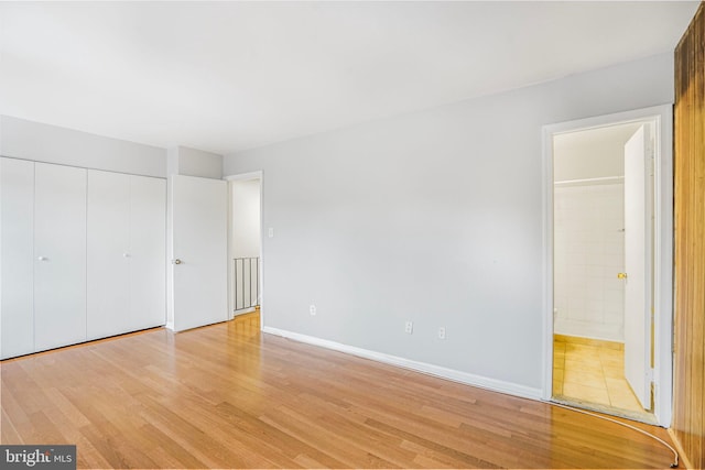 unfurnished bedroom featuring light wood-style flooring, baseboards, a closet, and connected bathroom