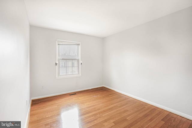 unfurnished room featuring light wood finished floors, visible vents, and baseboards