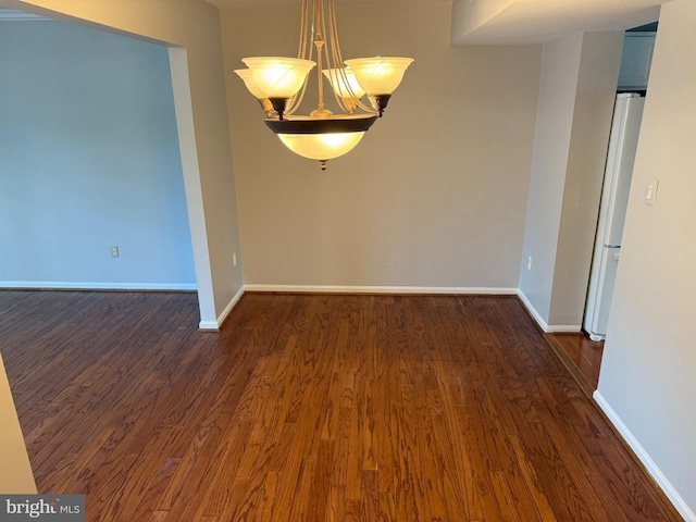 spare room with baseboards and dark wood-style flooring