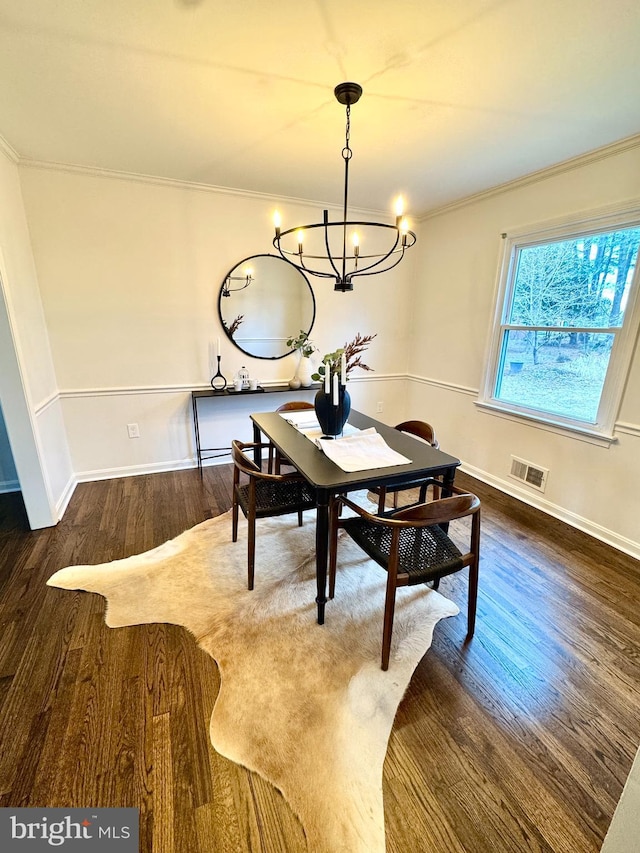 dining space featuring crown molding, a notable chandelier, visible vents, wood finished floors, and baseboards