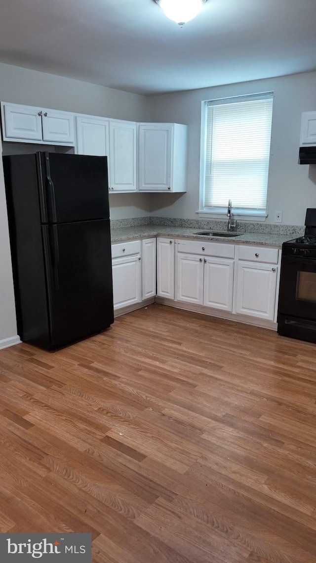 kitchen with white cabinetry, a sink, light wood finished floors, and black appliances