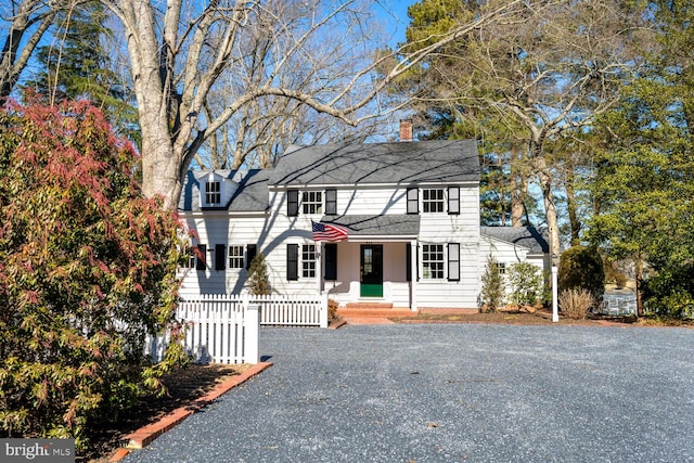 view of front of property with a shingled roof, a chimney, fence, and driveway