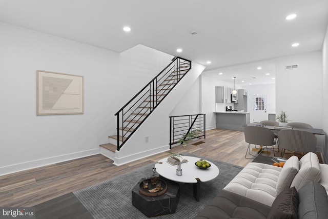 living room featuring baseboards, visible vents, stairs, light wood-type flooring, and recessed lighting