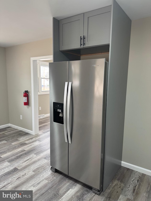 kitchen featuring light wood-style floors, gray cabinetry, baseboards, and stainless steel fridge with ice dispenser