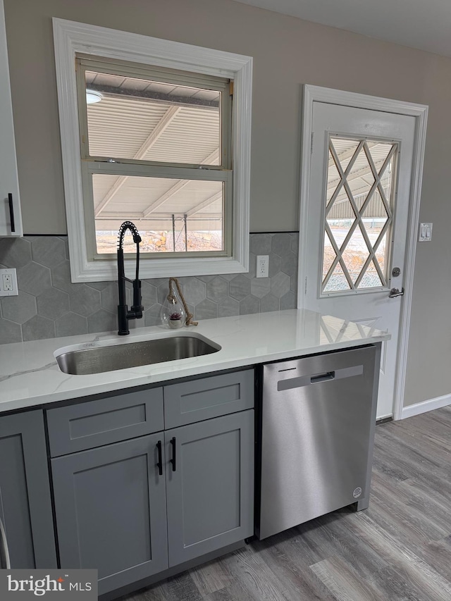 kitchen featuring a sink, light wood finished floors, gray cabinets, and stainless steel dishwasher