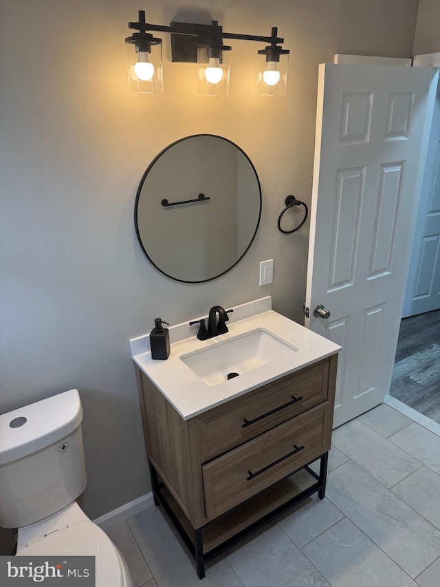 bathroom featuring marble finish floor, vanity, toilet, and baseboards