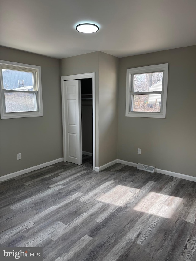 unfurnished bedroom with wood finished floors, visible vents, and baseboards