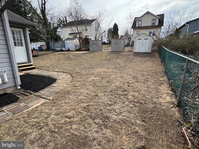 view of yard with entry steps, a shed, an outbuilding, and a fenced backyard