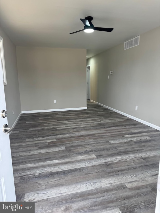 unfurnished room featuring dark wood-style flooring, visible vents, ceiling fan, and baseboards