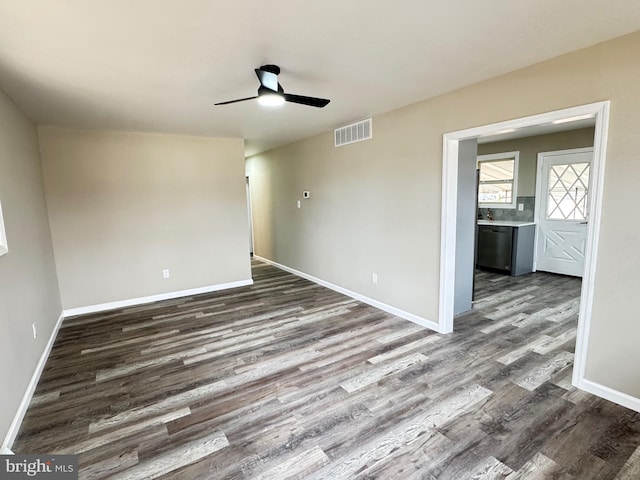 spare room featuring dark wood-style floors, baseboards, visible vents, and a ceiling fan