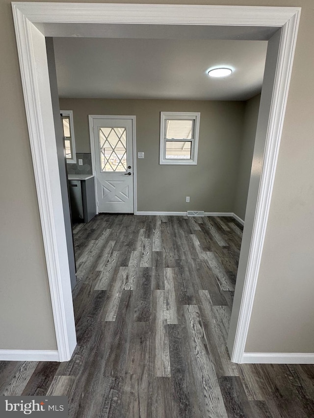 foyer entrance with dark wood-style flooring, visible vents, and baseboards