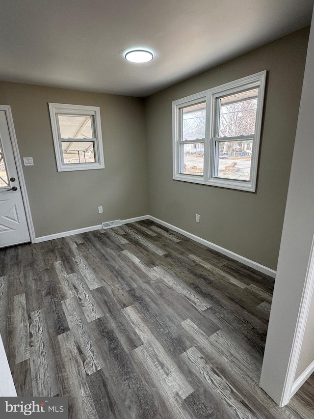 unfurnished room featuring a wealth of natural light, visible vents, and baseboards