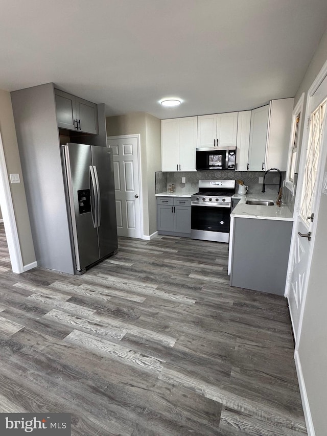 kitchen featuring tasteful backsplash, appliances with stainless steel finishes, gray cabinets, light countertops, and a sink