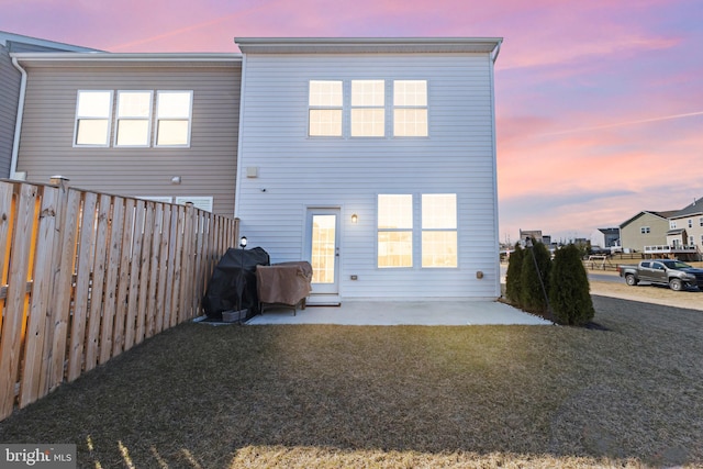 back of house featuring a patio area, a fenced backyard, and a lawn