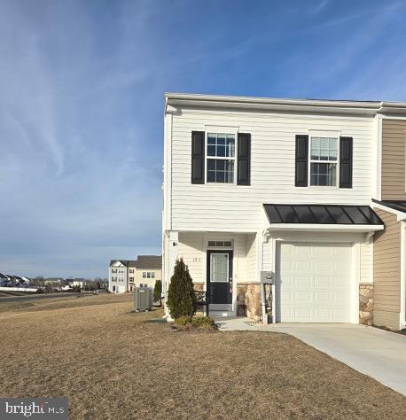 view of front of home featuring central air condition unit, a standing seam roof, metal roof, a garage, and driveway