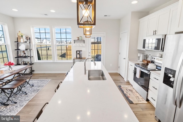 kitchen featuring light wood-type flooring, appliances with stainless steel finishes, light countertops, and a sink