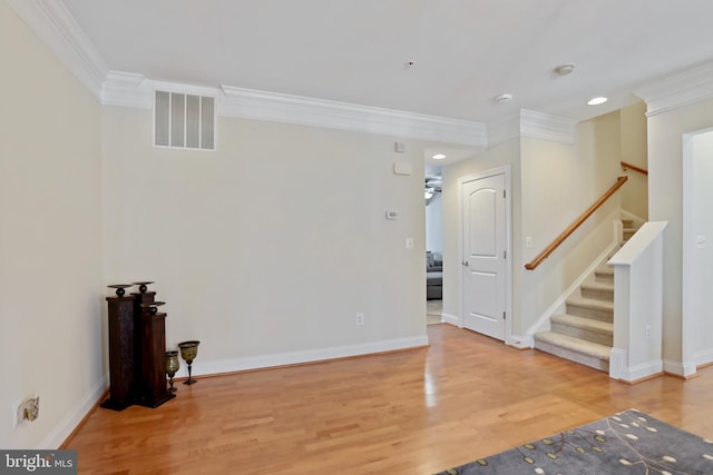 interior space featuring baseboards, visible vents, ornamental molding, wood finished floors, and stairs