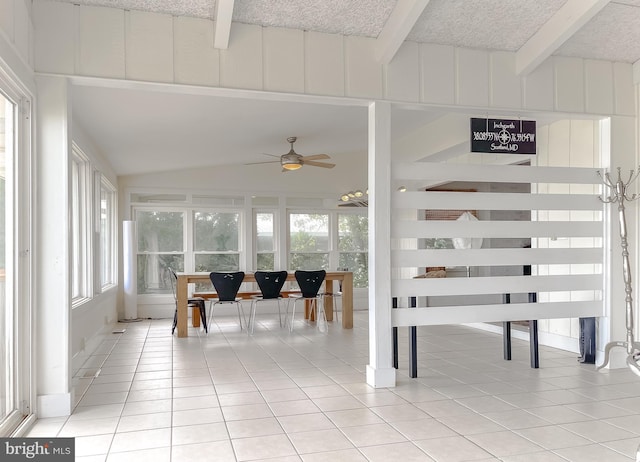 sunroom / solarium featuring a ceiling fan, a healthy amount of sunlight, and lofted ceiling with beams