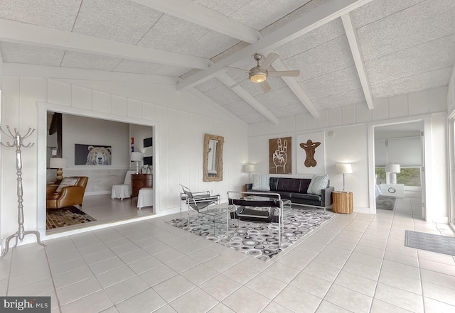 living room featuring a ceiling fan, light tile patterned flooring, and vaulted ceiling with beams