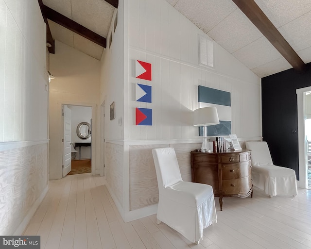 hallway with high vaulted ceiling, beamed ceiling, and light wood-style floors