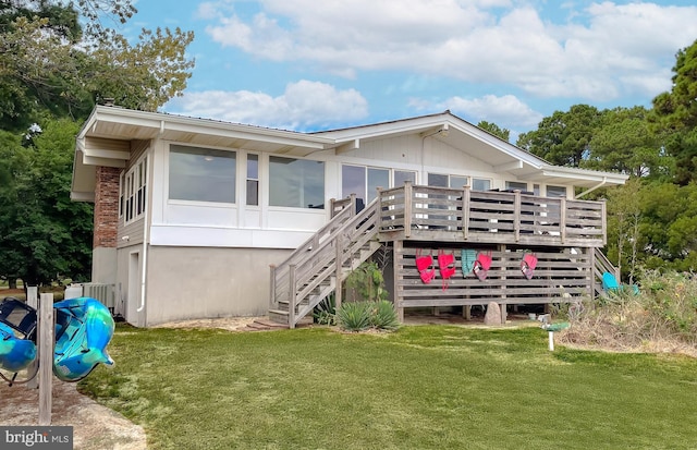 back of property featuring a sunroom, a lawn, stairway, and a wooden deck