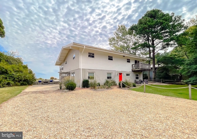 rear view of house featuring driveway, a lawn, and a wooden deck