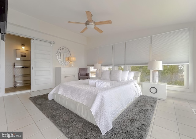 bedroom featuring light tile patterned floors, ceiling fan, and a barn door