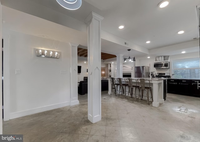 kitchen with a breakfast bar, stainless steel appliances, recessed lighting, an island with sink, and baseboards