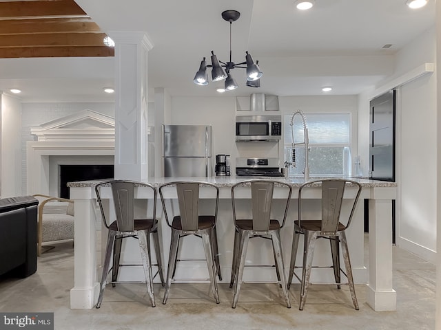 kitchen featuring stainless steel appliances, a kitchen breakfast bar, open floor plan, light stone countertops, and pendant lighting