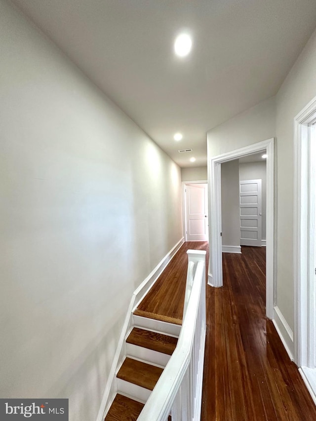 hall with visible vents, baseboards, dark wood finished floors, and recessed lighting