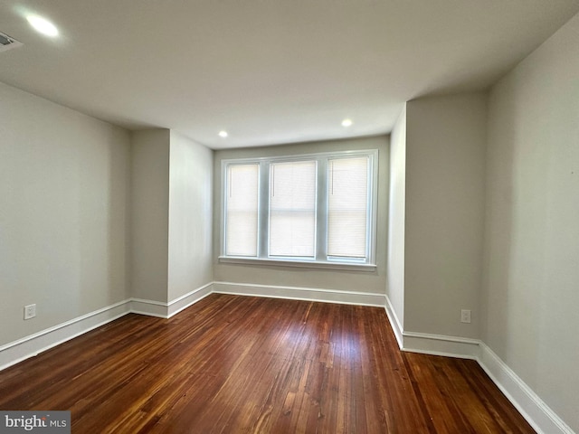 empty room with dark wood-style floors, visible vents, baseboards, and recessed lighting