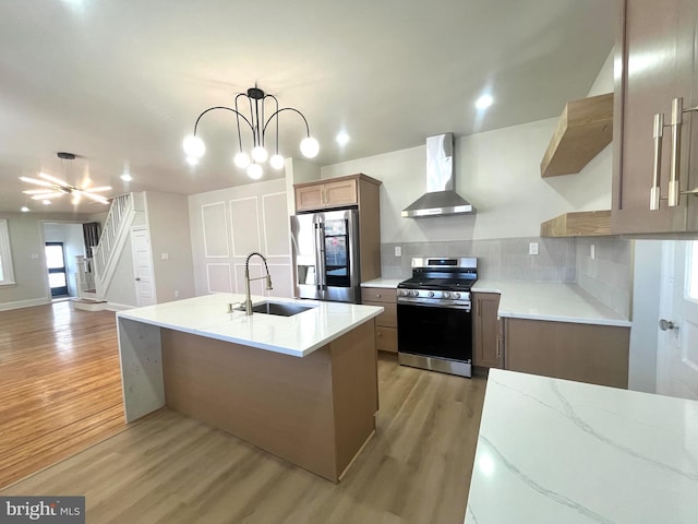 kitchen with decorative light fixtures, stainless steel appliances, light countertops, a sink, and wall chimney exhaust hood