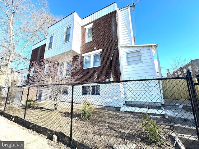 view of side of home featuring brick siding and fence