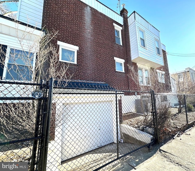 view of property exterior with a gate, brick siding, and fence