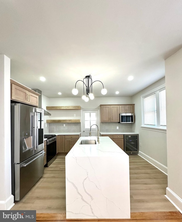 kitchen featuring beverage cooler, stainless steel appliances, a sink, open shelves, and a center island with sink